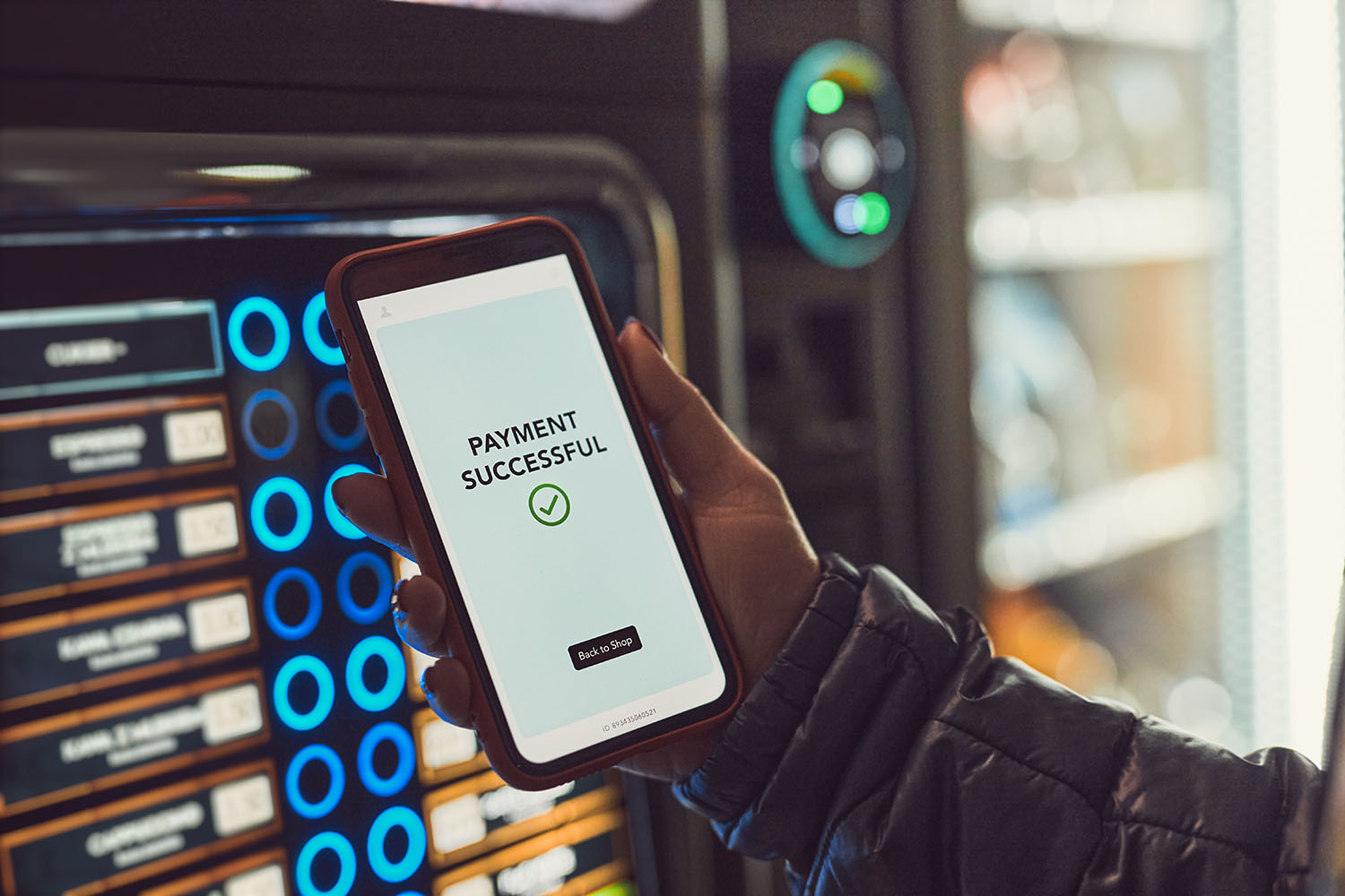 A person's hand holding a smartphone with a payment successful message on the screen,